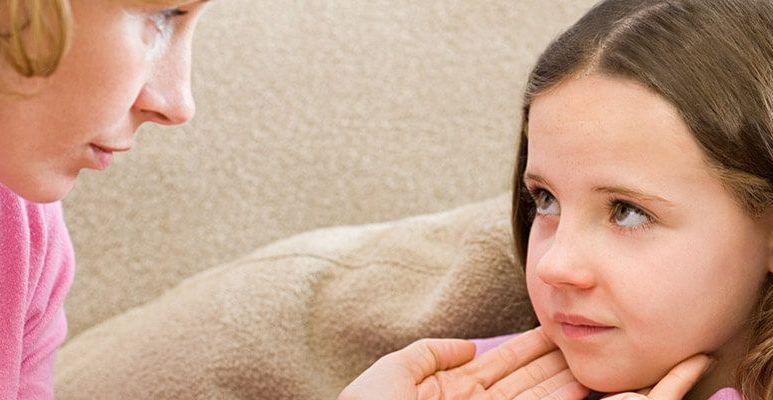 Mama dotyka twarzy córeczki, która wykazuje objawy zakażenia mononukleozą