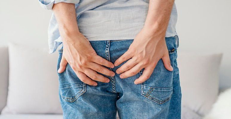 Mężczyzna trzyma się rękami za pośladki