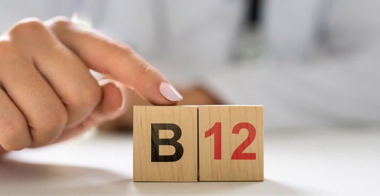 Osoba trzyma palec na drewnianej tabliczce z nazwą witaminy B12