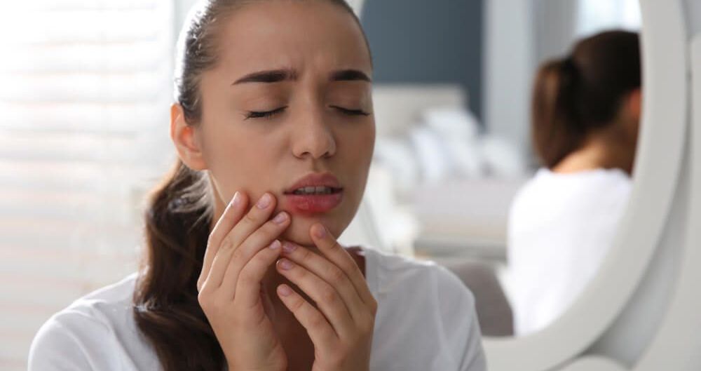 Młoda kobieta dotyka ust, na których znajdują się bolesne pęcherze