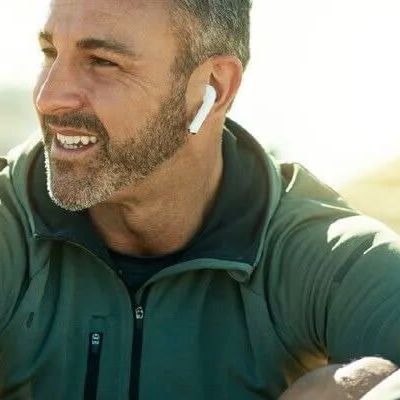 Uśmiechnięty mężczyzna w zielonej bluzie i słuchawkami w uszach