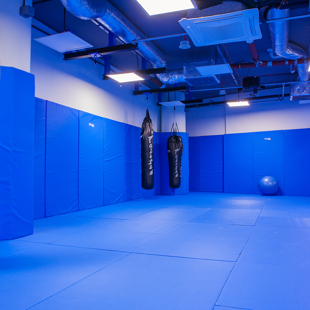 Sala do sztuk walki z niebieskimi matami i workiem treningowym.
