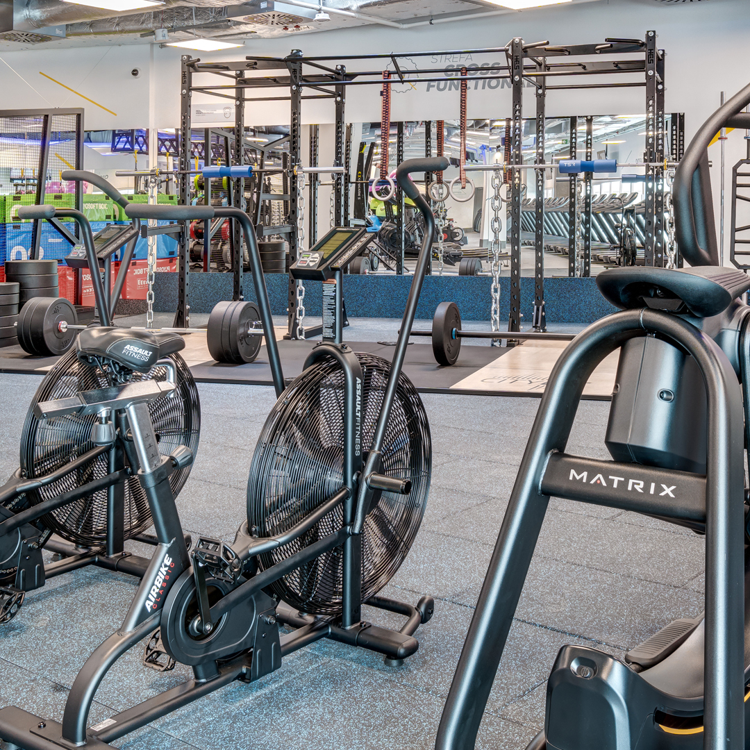 Siłownia z rowerami, sztangami i ciężarami.