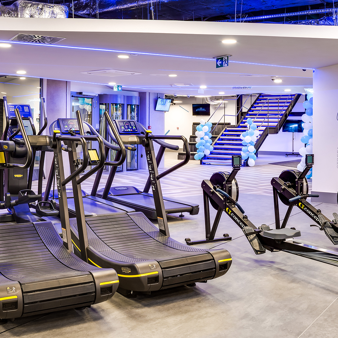 Treningowe urządzenia eliptyczne w siłowni z nowoczesnymi ekranami.