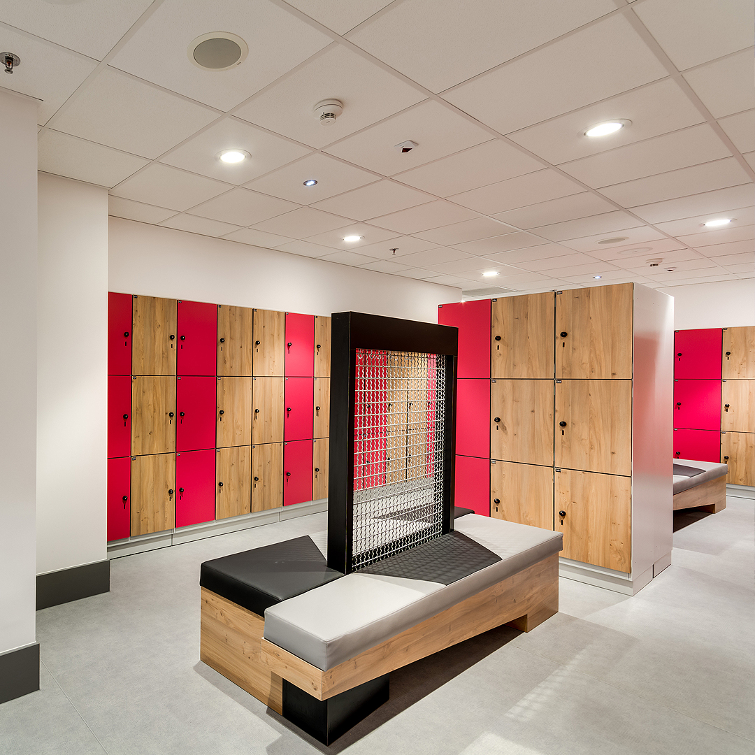 Szafki w szatni z czerwonymi i drewnianymi drzwiami.